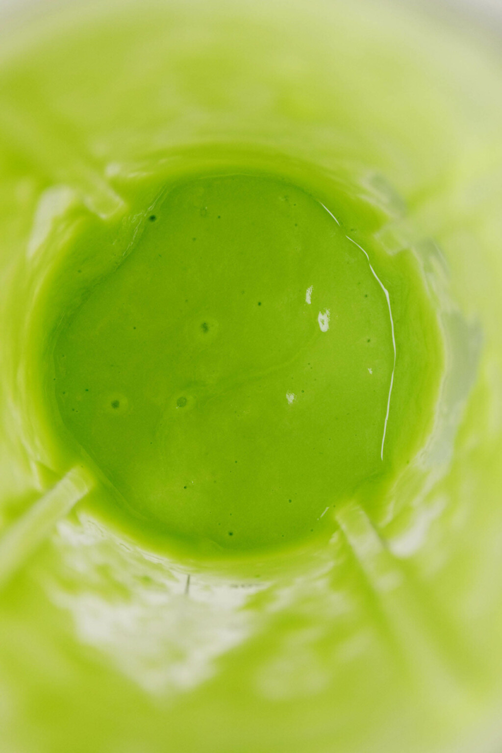 An overhead image of a creamy green dressing that has just been prepared in a handheld blender.