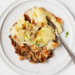 A round dinner plate is piled with a plant-based comfort food dish of vegetables and mashed potatoes.