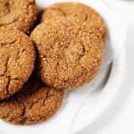 A few vegan molasses ginger cookies are piled onto a plate.