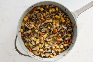 A gray pot holds cooked mushrooms and vegetables.