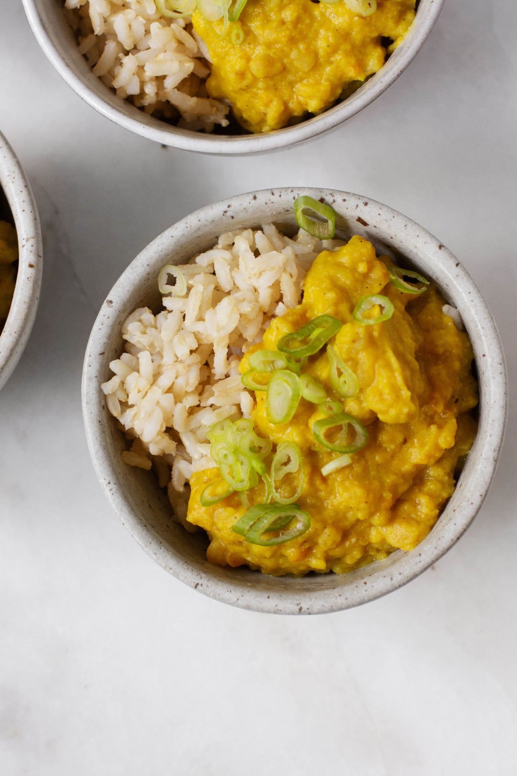 A photograph of rich, golden split pea coconut breakfast porridge, served over brown rice.