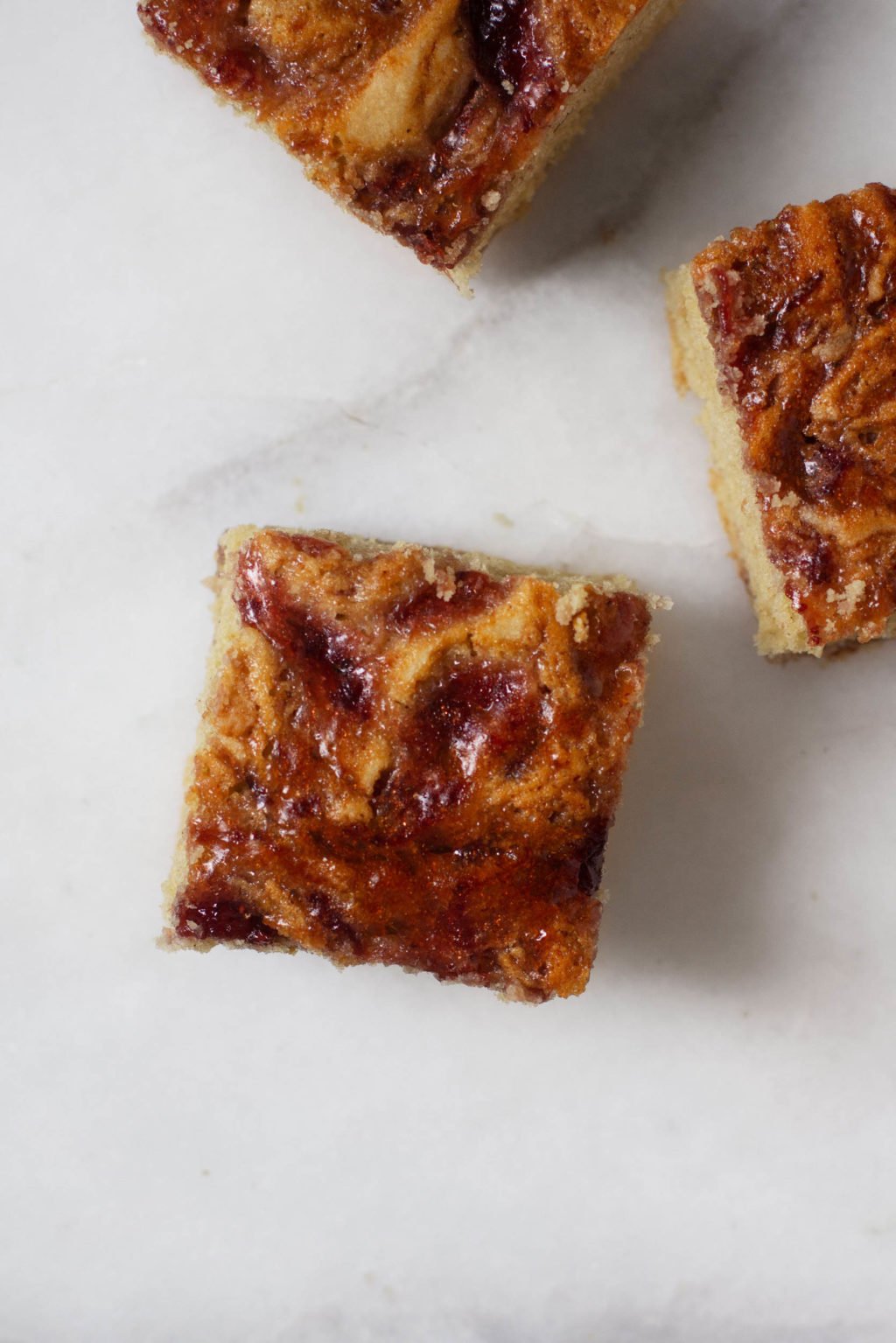 Cut squares of a PB&J inspired snacking cake, with swirls of jam on top.