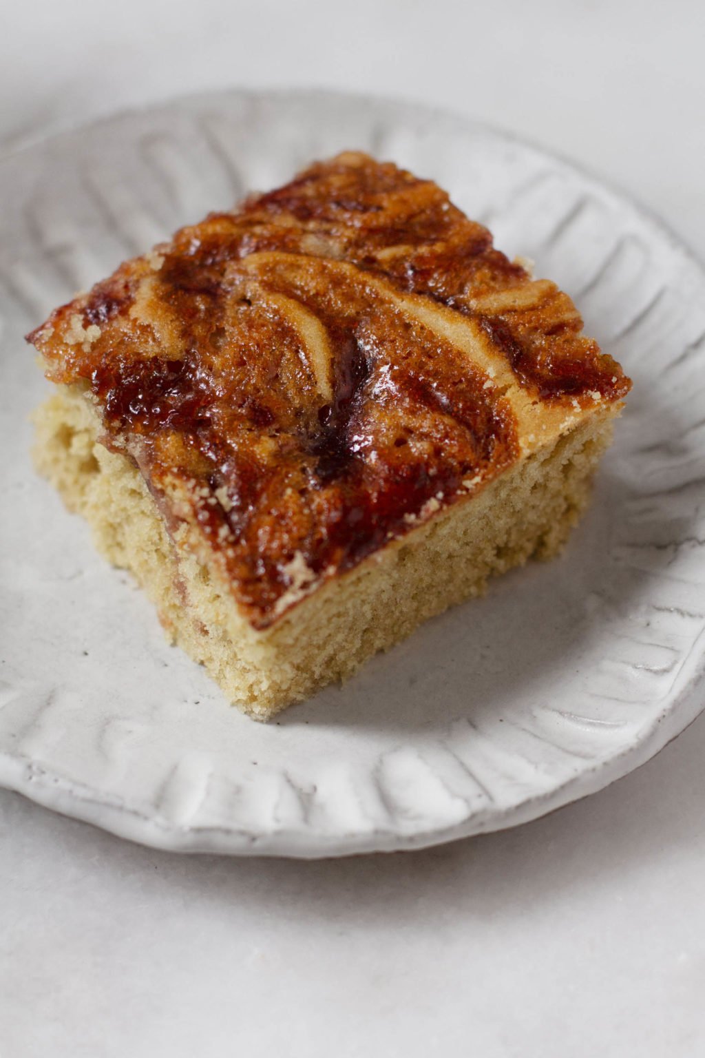 A fluffy, freshly cut slice of plated vegan peanut butter and jelly snacking cake.