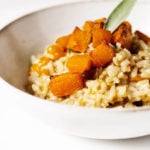 An angled shot of a vegan butternut squash risotto, garnished with sage.