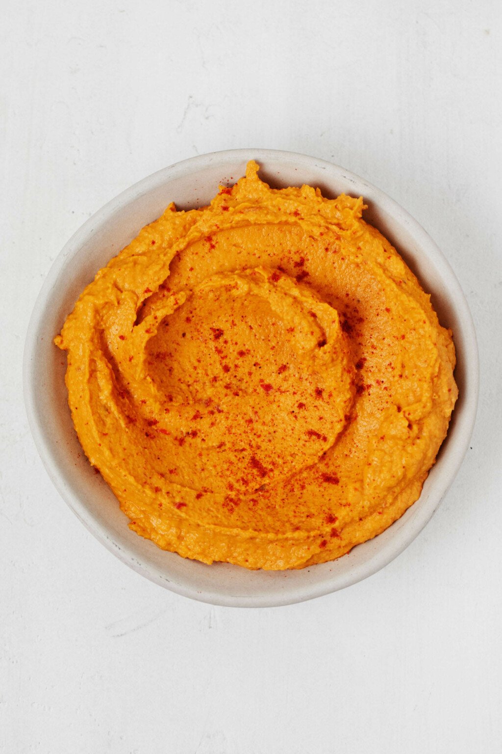 An overhead image of a small bowl of creamy vegan sweet potato hummus.