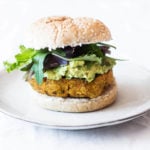 A vegan burger made with edamame and sweet potatoes is served with guacamole on a burger bun.