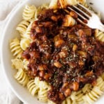 A bowl full of white bean pasta and tomato sauce rests on a linen napkin.