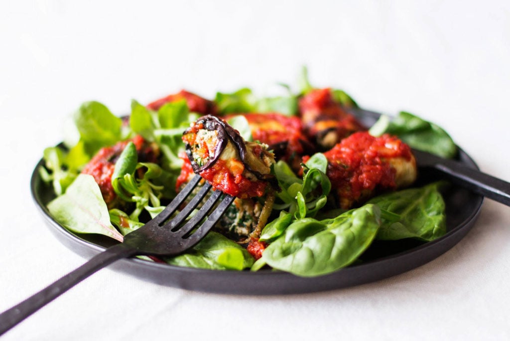 A vegan eggplant roll is being served with a black fork.