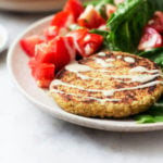 A side angled photograph of a quinoa chickpea zaatar burger patty, served with lettuce wraps and tahini dressing.