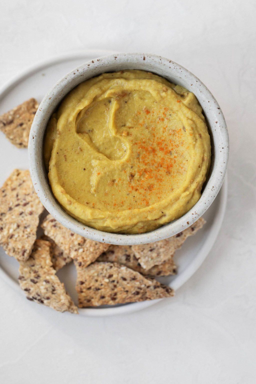 An overhead image of a smoky eggplant red lentil dip, which is held in a white pinch bowl.