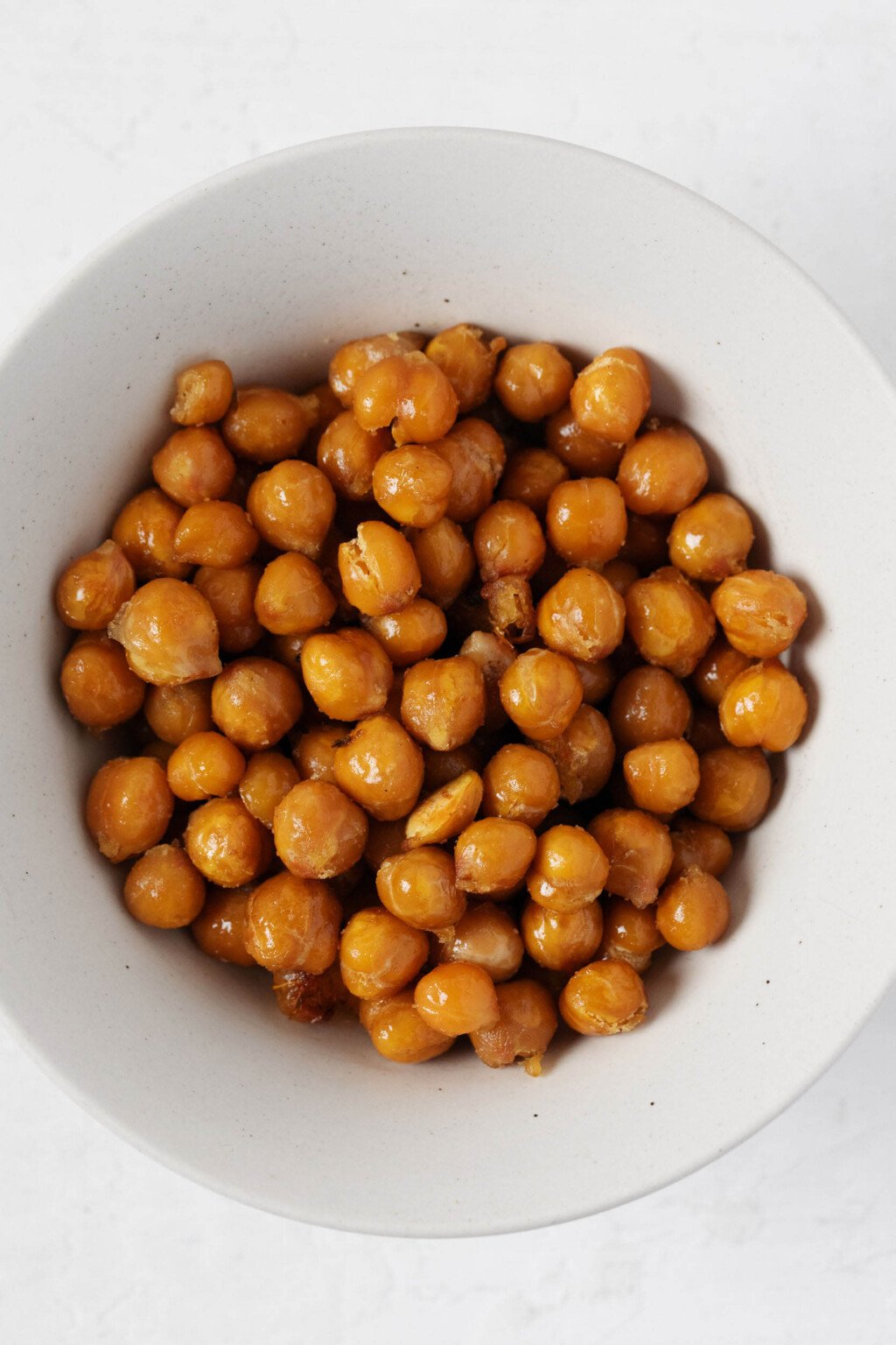 An overhead image of oven-roasted chickpeas, which have been placed into a white bowl.