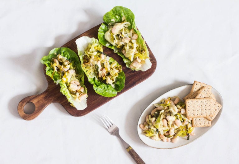 Vegan hors d'oeuvres with beans and crackers have been served, along with lettuce leaves.