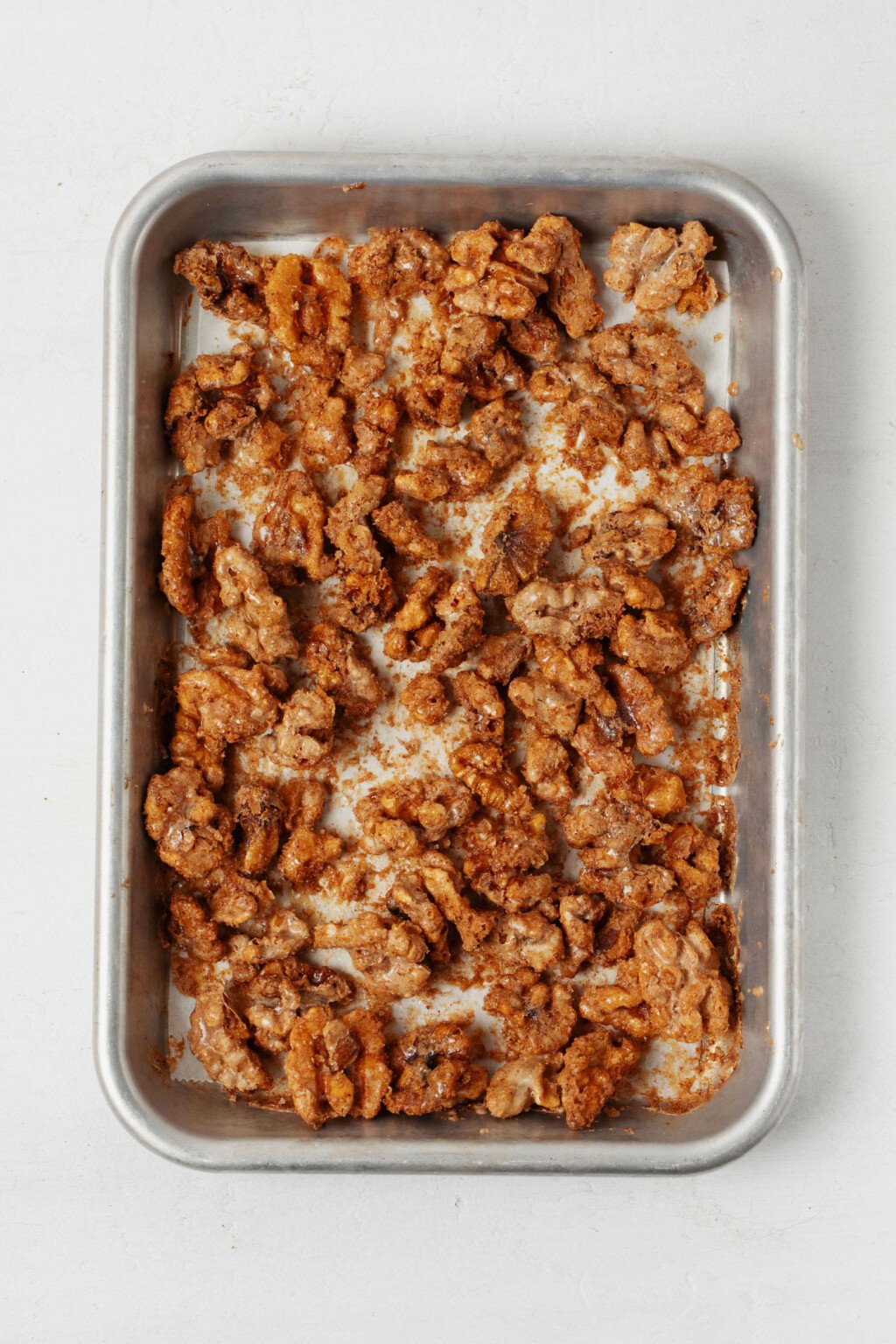 Vegan candied walnuts have just been baked and are cooling on a baking sheet.