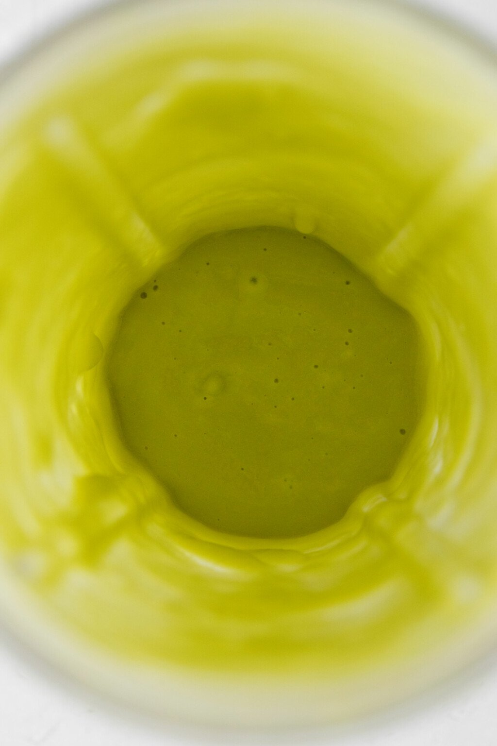 An overhead image of a pale green, avocado vanilla pudding in a mini-blender.