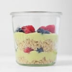 A weck mason jar is filled with layers of cooked quinoa, berries, and a creamy, vanilla lemon avocado pudding.