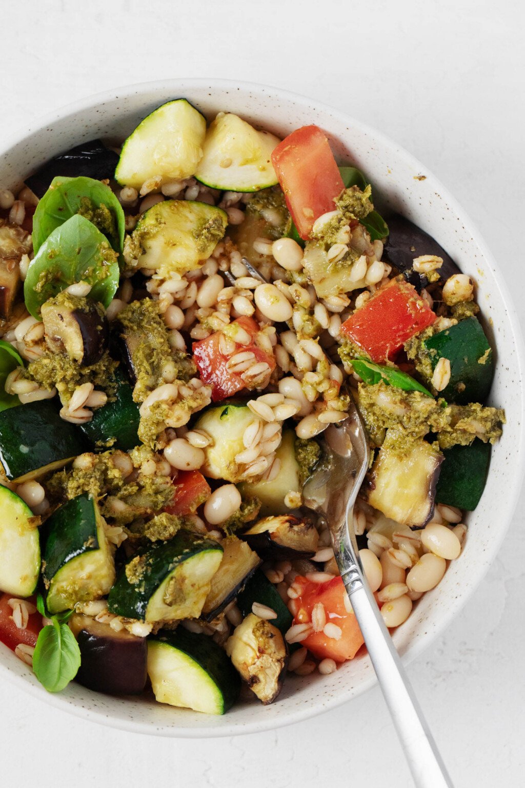 Cooked barley and colorful roasted summer vegetables have been mixed together with pesto sauce.