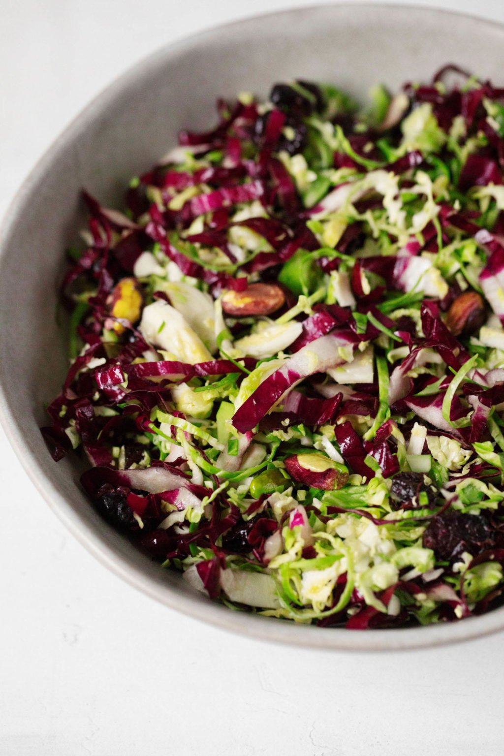 Brussels sprouts have been shaved into thin pieces and are used in a colorful winter salad.