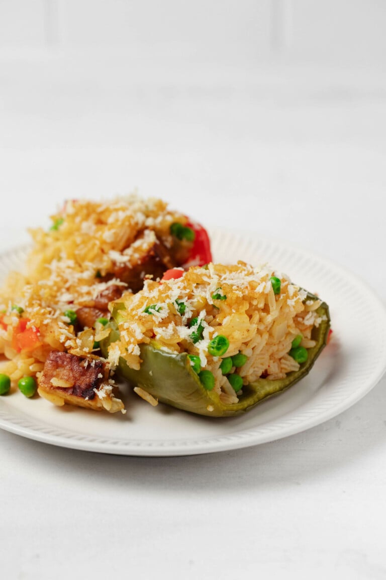 A vegan stuffed pepper dish has been plated on a white, rimmed plate. It rests on a white surface.