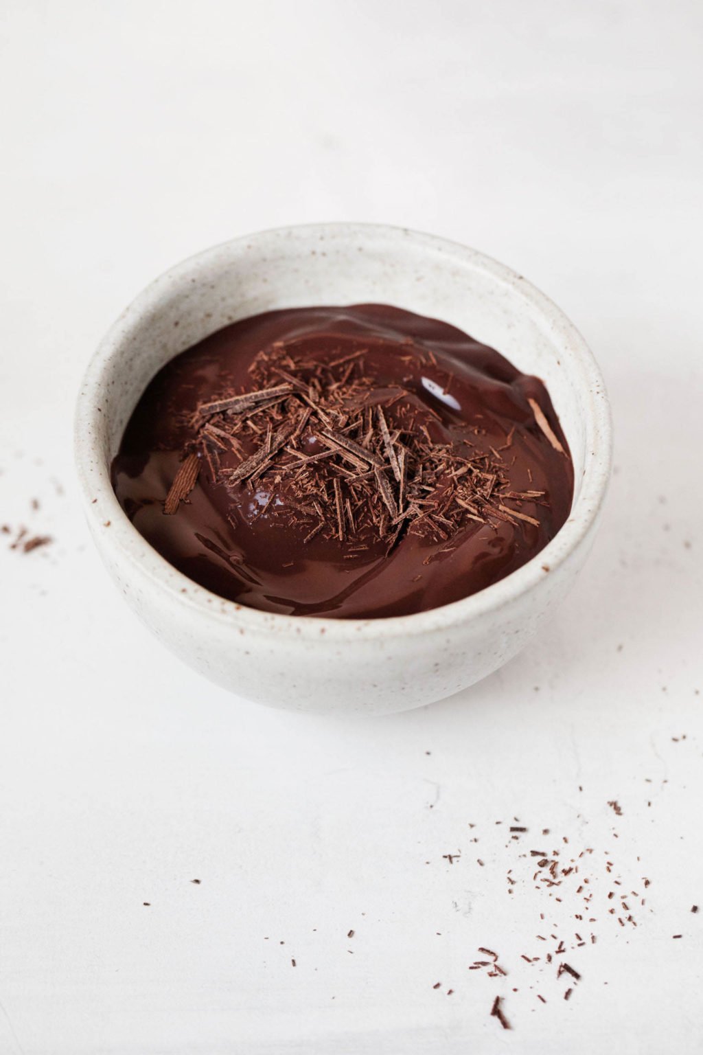 A single, small ceramic bowl is resting on a white surface. It's filled with a vegan cashew chocolate pudding.