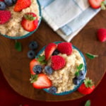 A few small glass containers hold a creamy vegan quinoa breakfast pudding and berries