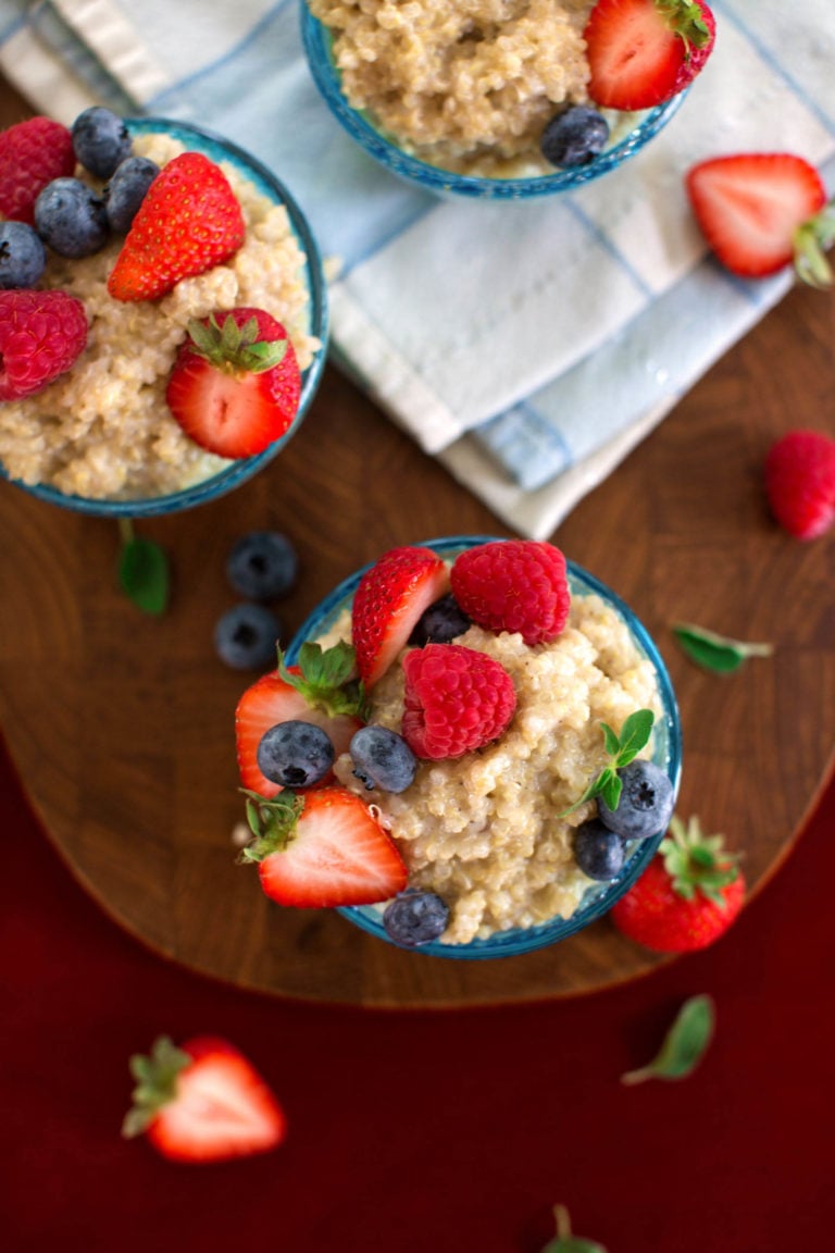 A few small glass containers hold a creamy vegan quinoa breakfast pudding and berries