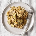 A ceramic plate rests on a gray linen cloth. It holds a cheesy vegan quinoa bake.