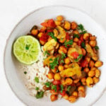 A white, rimmed bowl has been filled with a bed of cooked rice and a scrambled chickpea mixture, then sprinkled with bright green parsley.