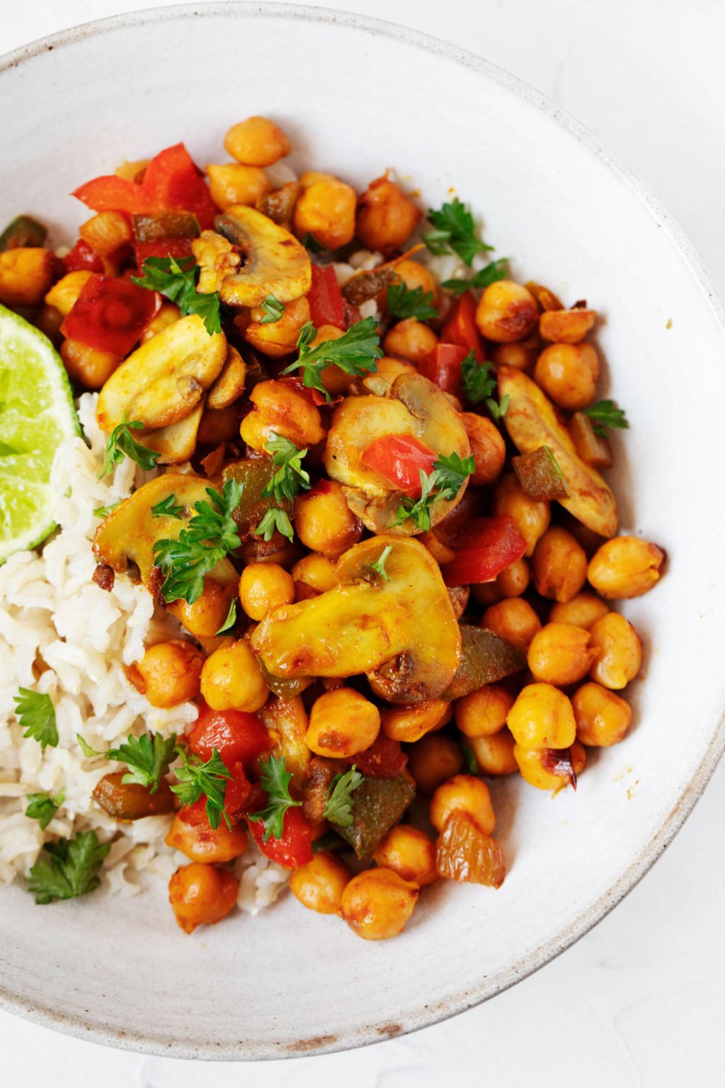 An overhead image of a vegan chickpea scramble, which has been seasoned with red chili powder and other spices. It is garnished with chopped parsley.