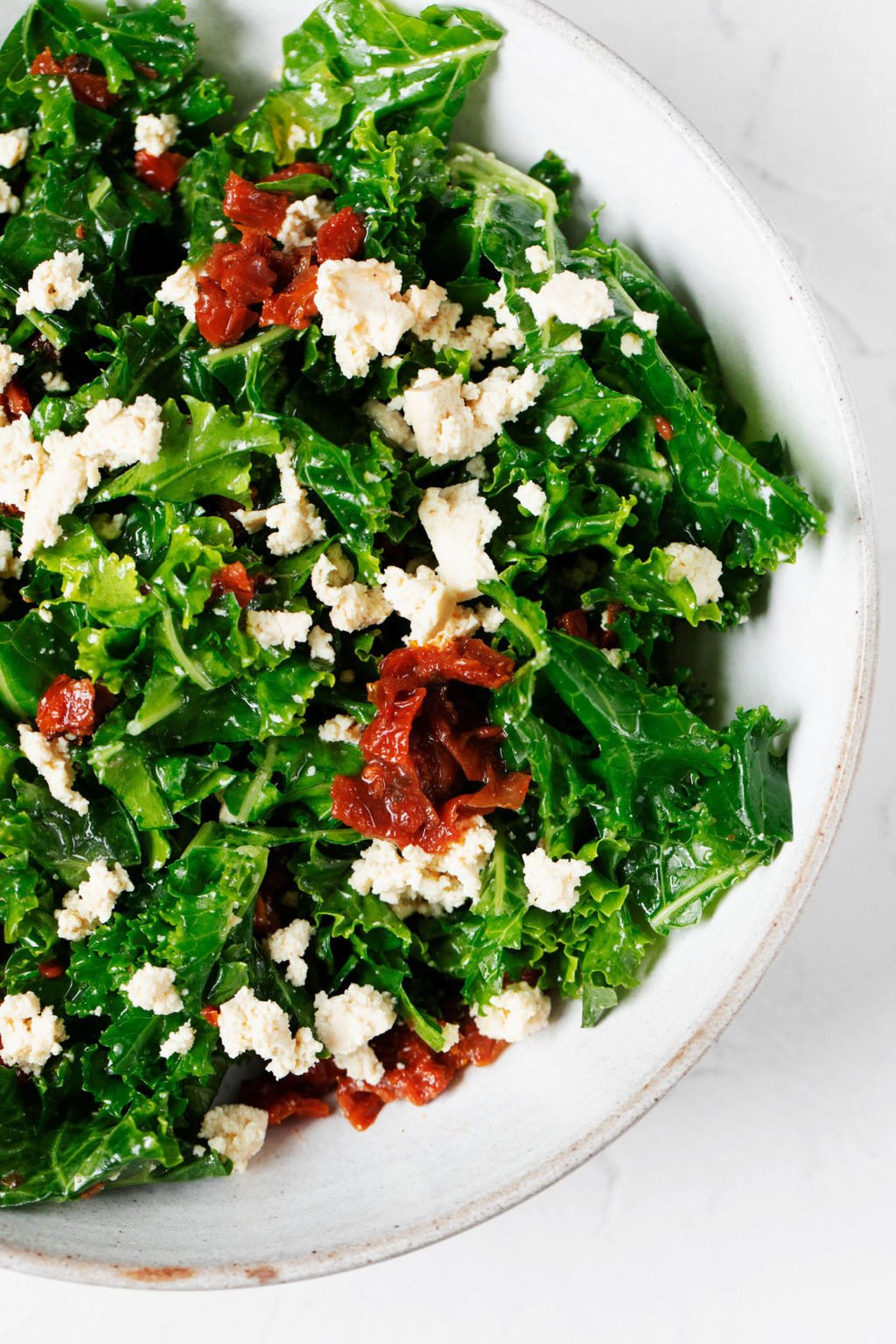 An overhead image of a leafy green salad with plant-protein in a white bowl.