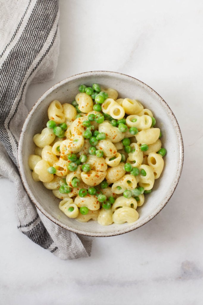 An overhead shot of vegan, gluten free mac n' cheese with green peas.