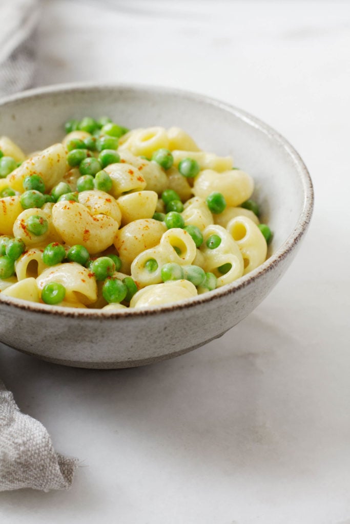 A sideways shot of vegan mac n' cheese, featuring the addition of green peas.