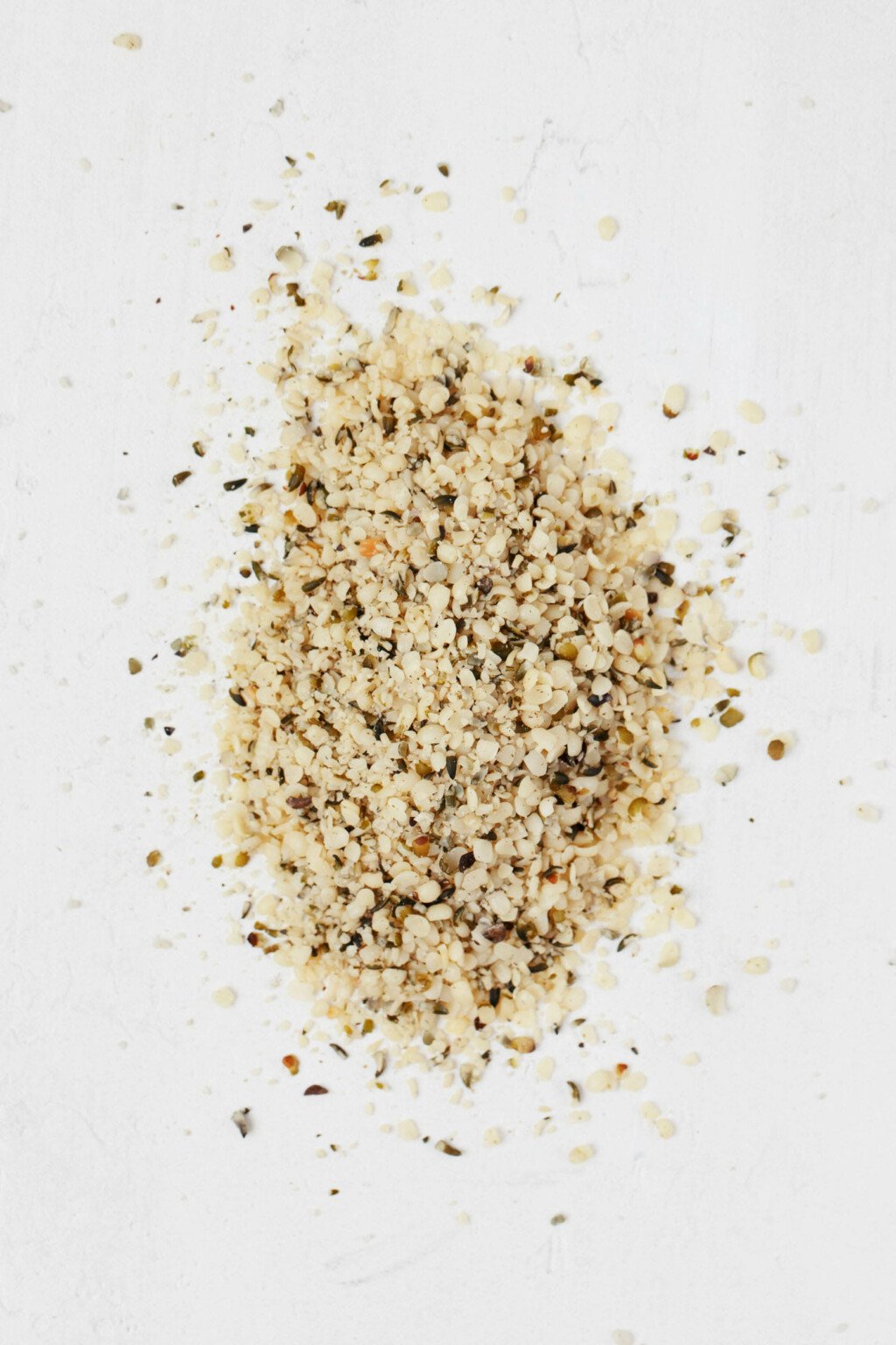An image of shelled hemp seeds, resting on a white surface.