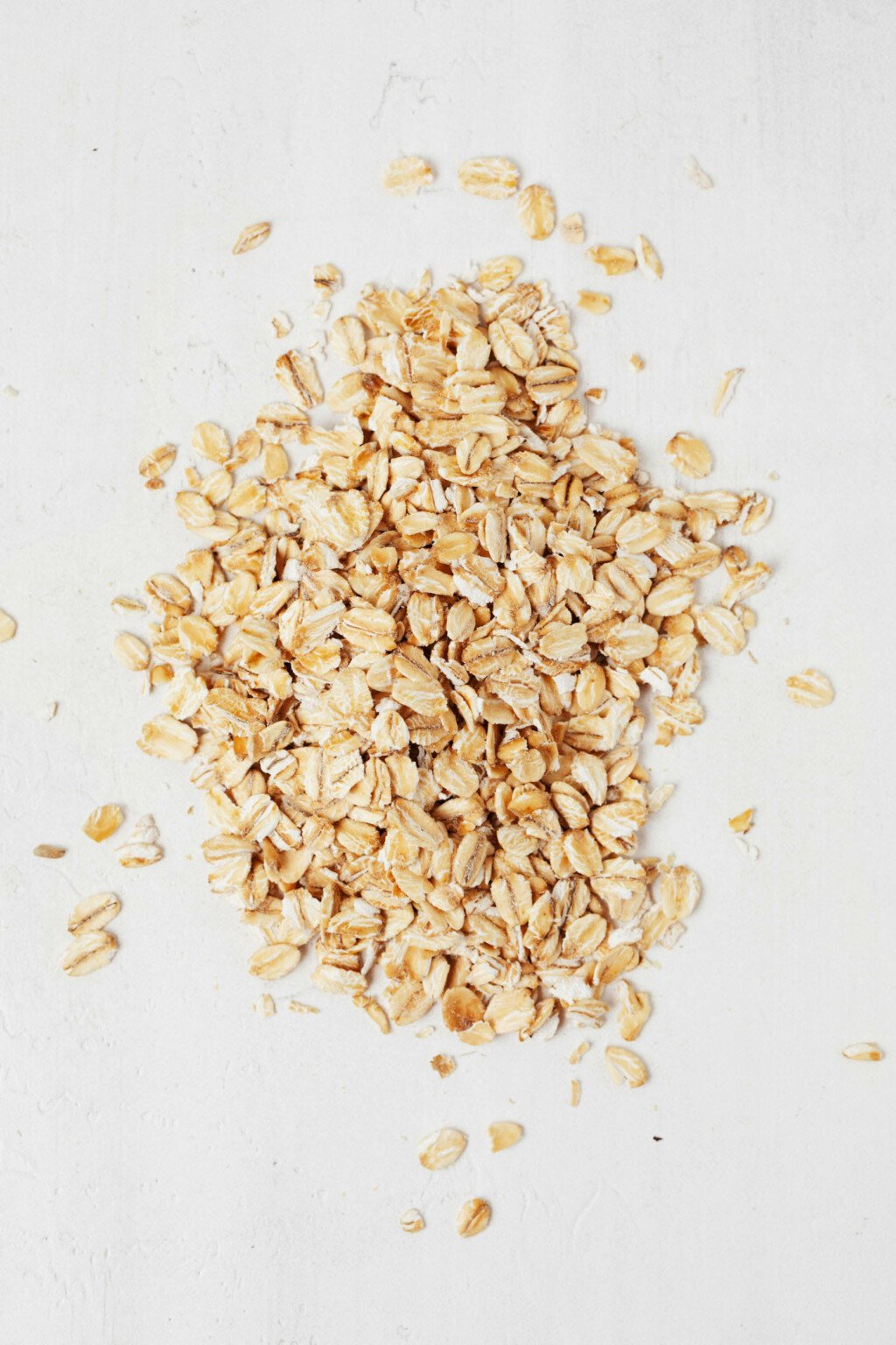 An image of rolled oats, resting on a white surface.