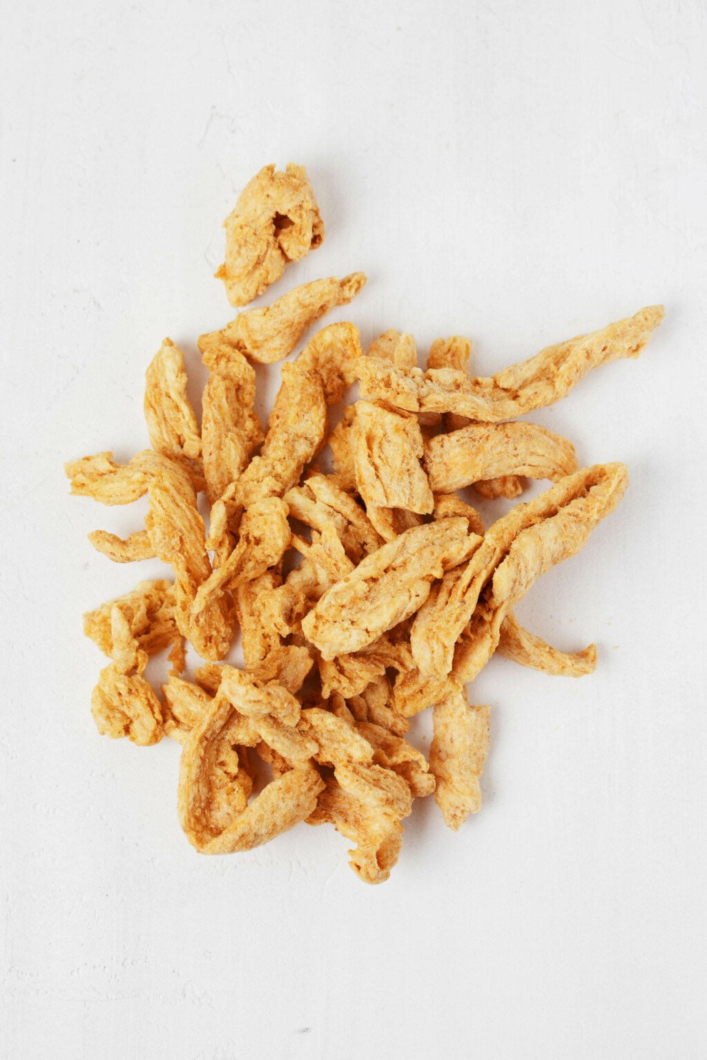 An overhead image of soy curls on a white surface.