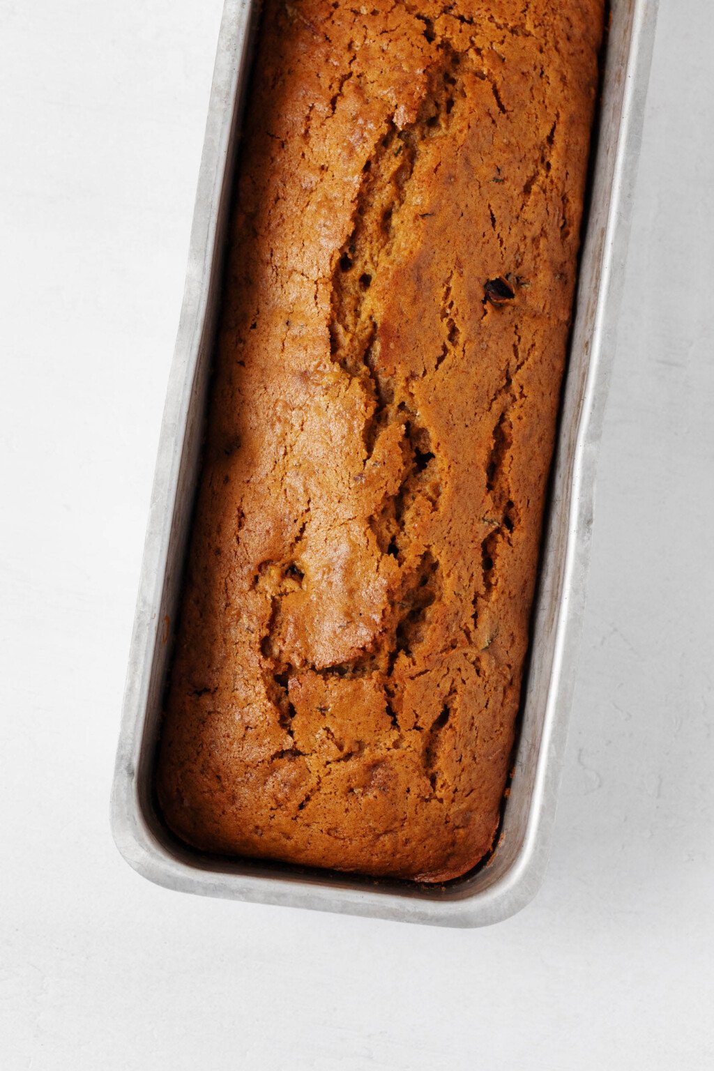 Vegan zucchini bread is pictured in a long, rectangular pullman pan.