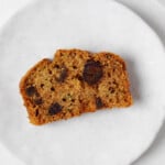 An overhead image of a moist slice of zucchini date bread, arranged on a small, round white plate.