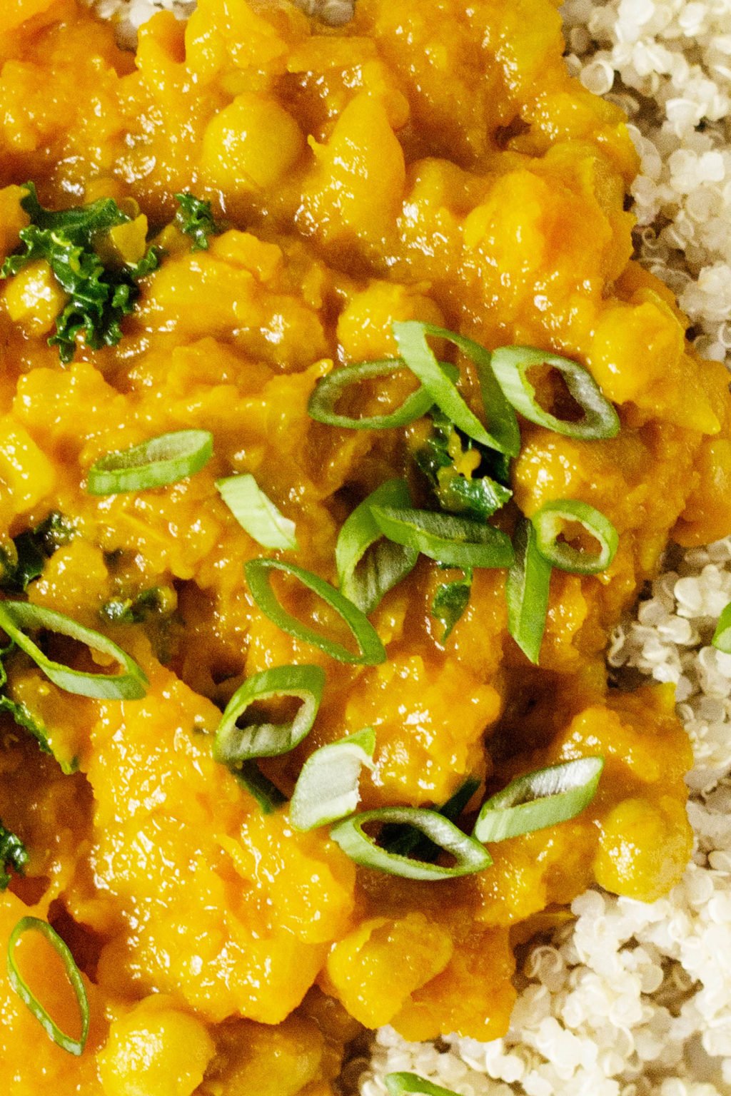 Bright and beautifully colored, vegan golden butternut squash and chickpea curry is garnished with chopped green onion tops. It's served with a whole grain for a fast and nourishing plant based meal. 