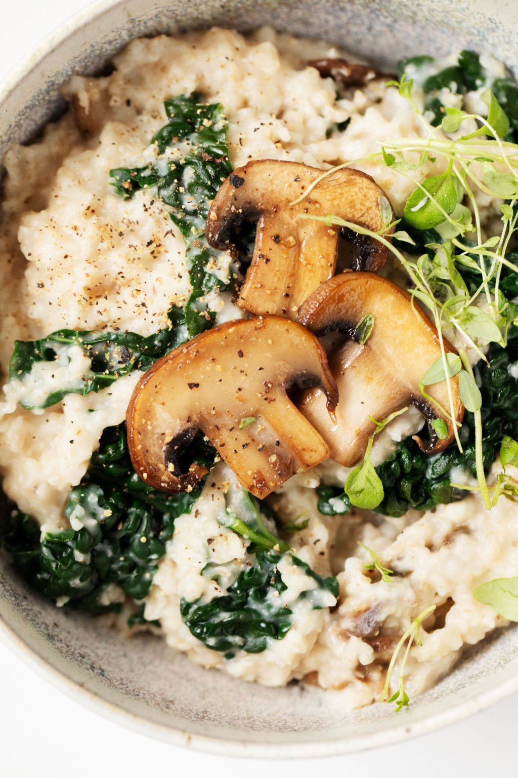 A close up photograph of a savory, whole grain breakfast with mushrooms and greens.