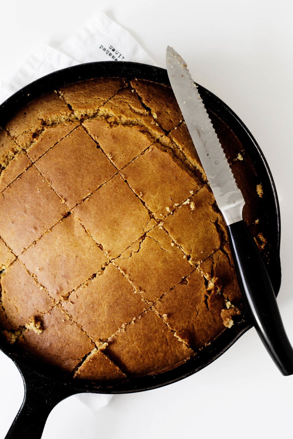 A skillet full of warm cornbread. The cornbread has been cut into squares, ready for eating. 