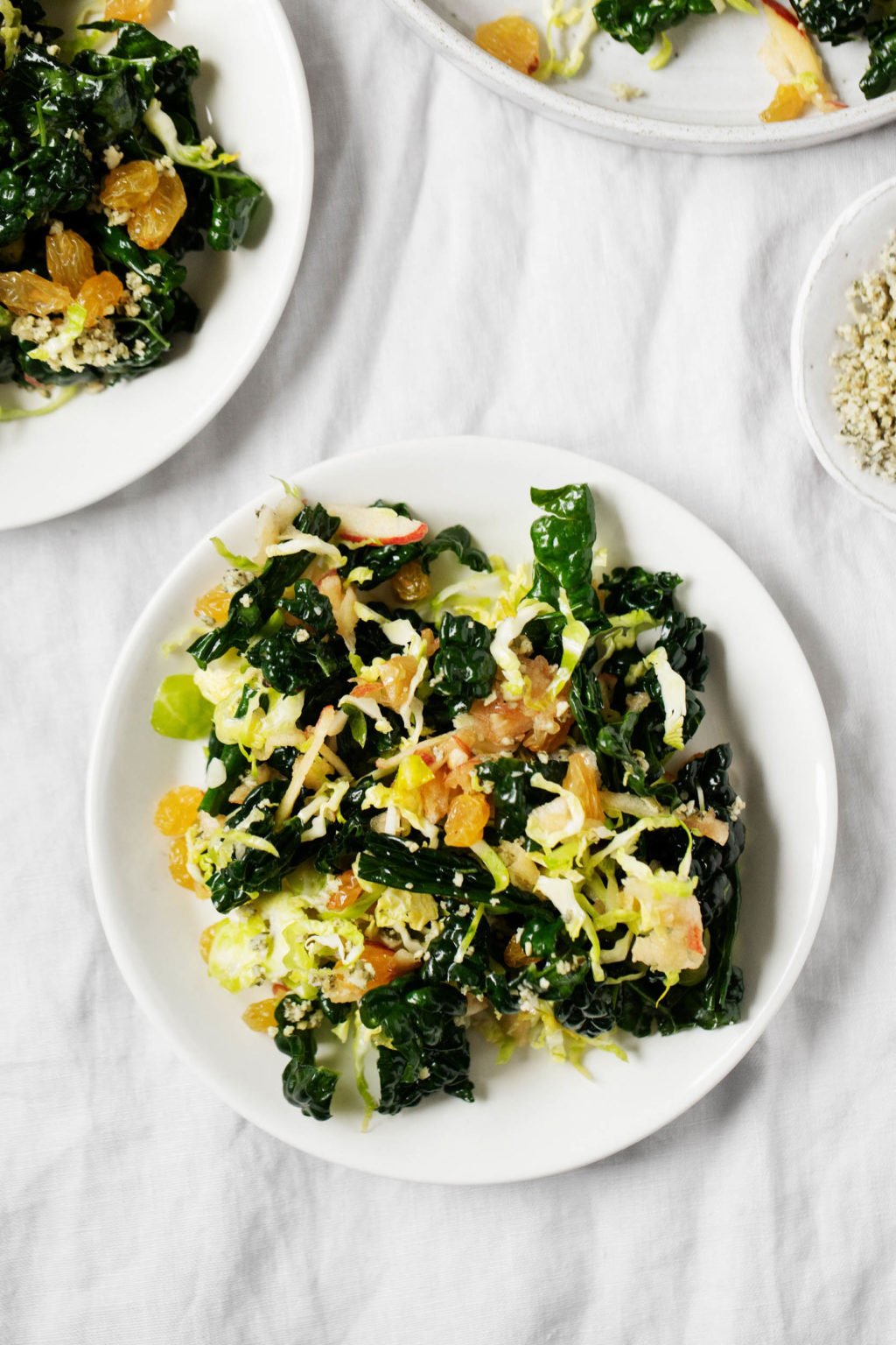 A few plates of kale salad, which has been made with shaved Brussels sprouts and topped with a plant-based seed topping.