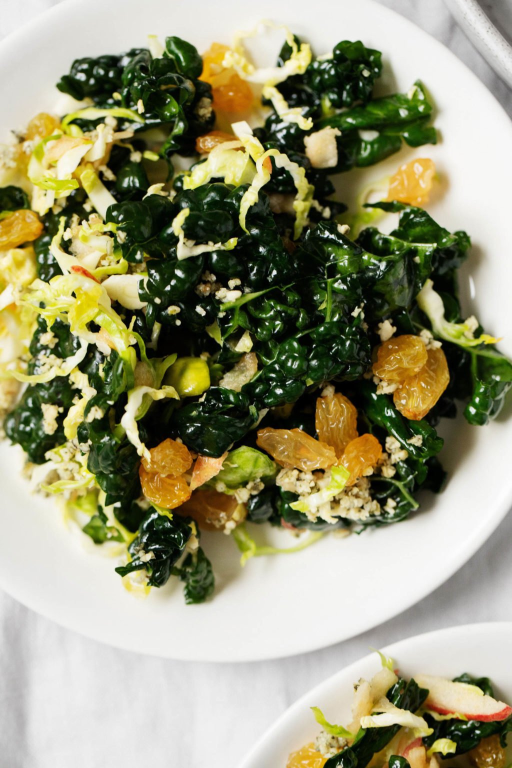 A zoomed in photograph of a serving plate, which is topped with a Brussels sprout kale salad.