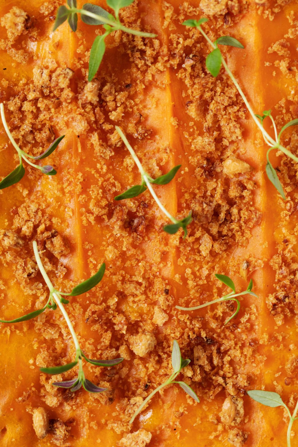 A vegan holiday dish is made with a mashed sweet potato topping, which is then decorated with bread crumbs and thyme sprigs.