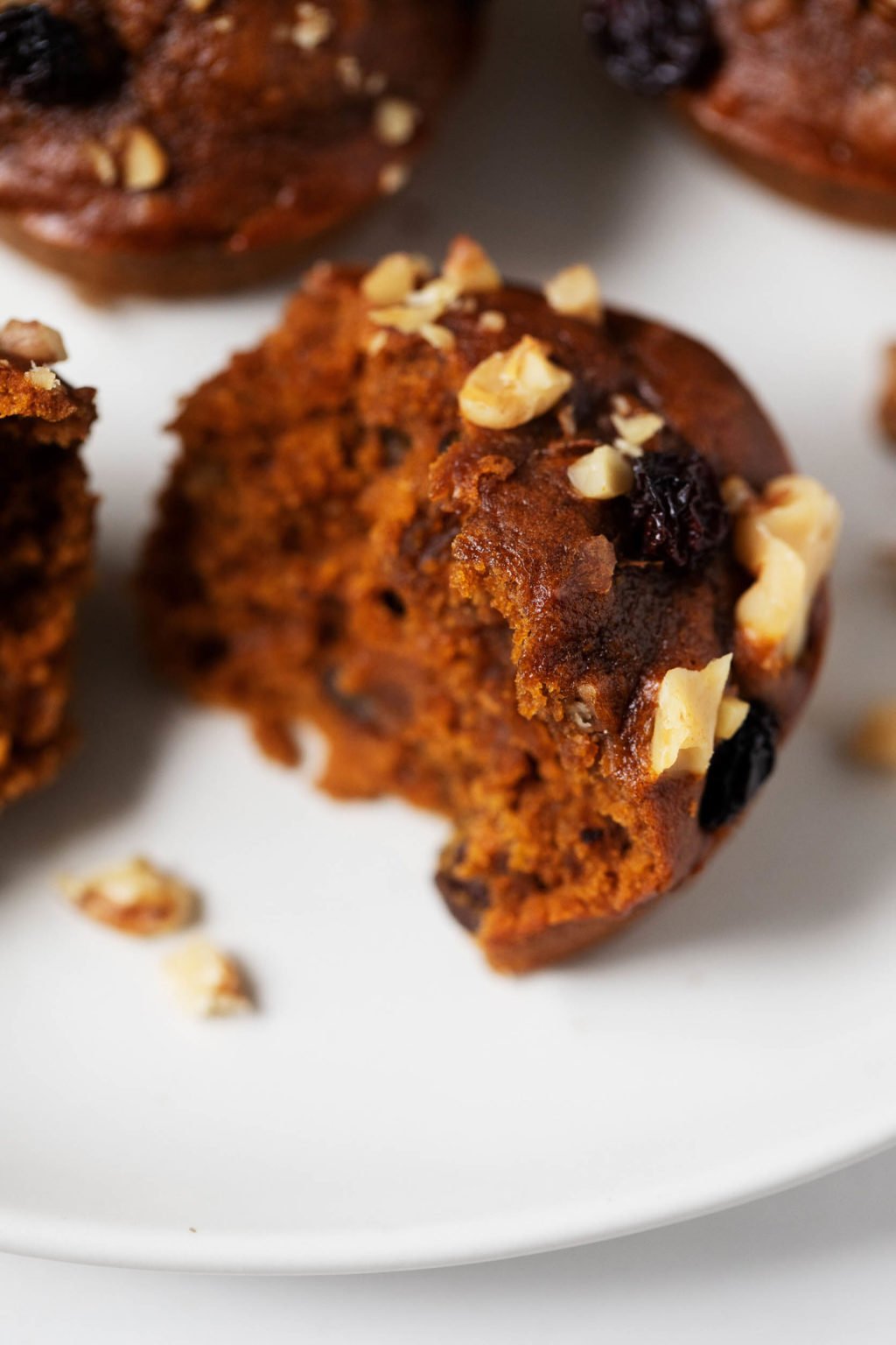 An angled photograph of a vegan pumpkin gingerbread spice muffin, broken apart into fluffy pieces and ready to eat.