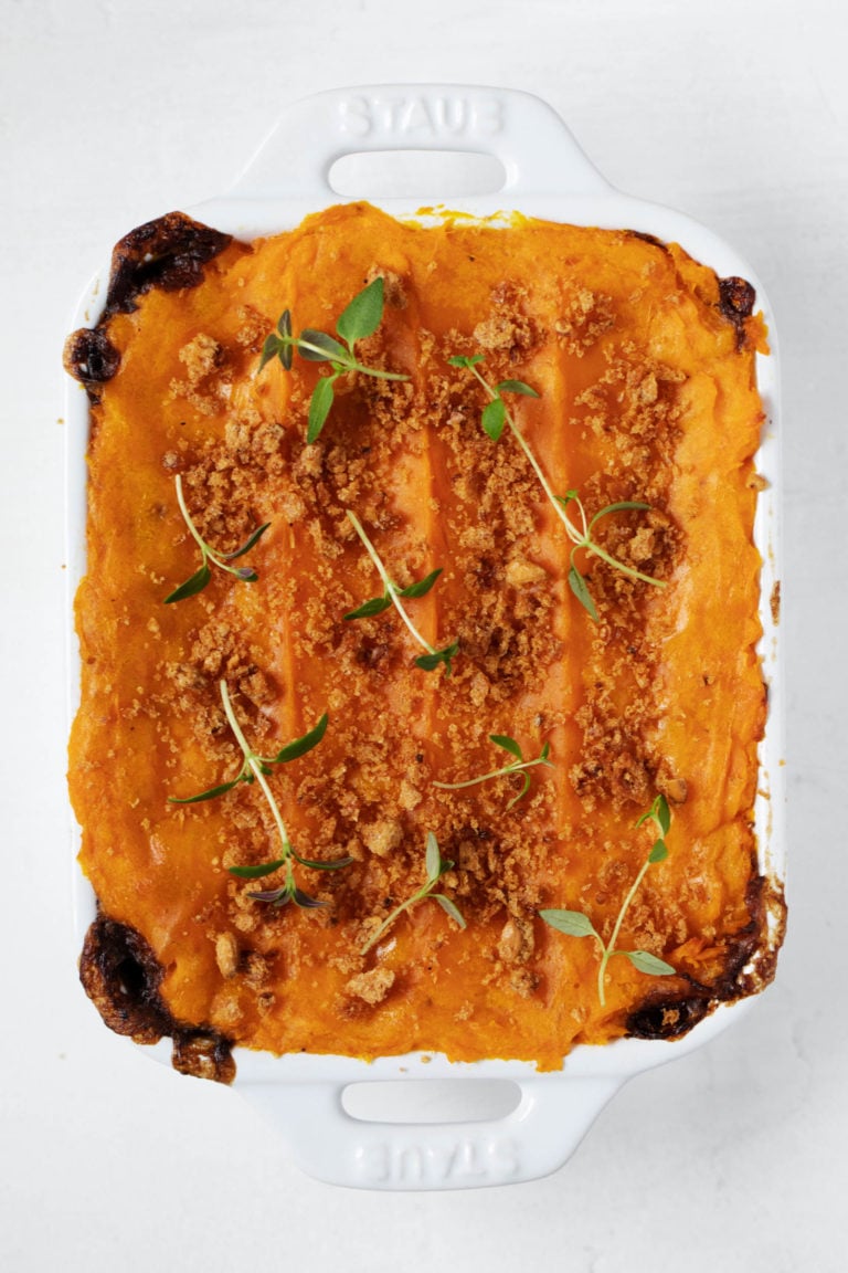 A small, rectangular baking dish is filled with a vegan sweet potato lentil shepherds pie.