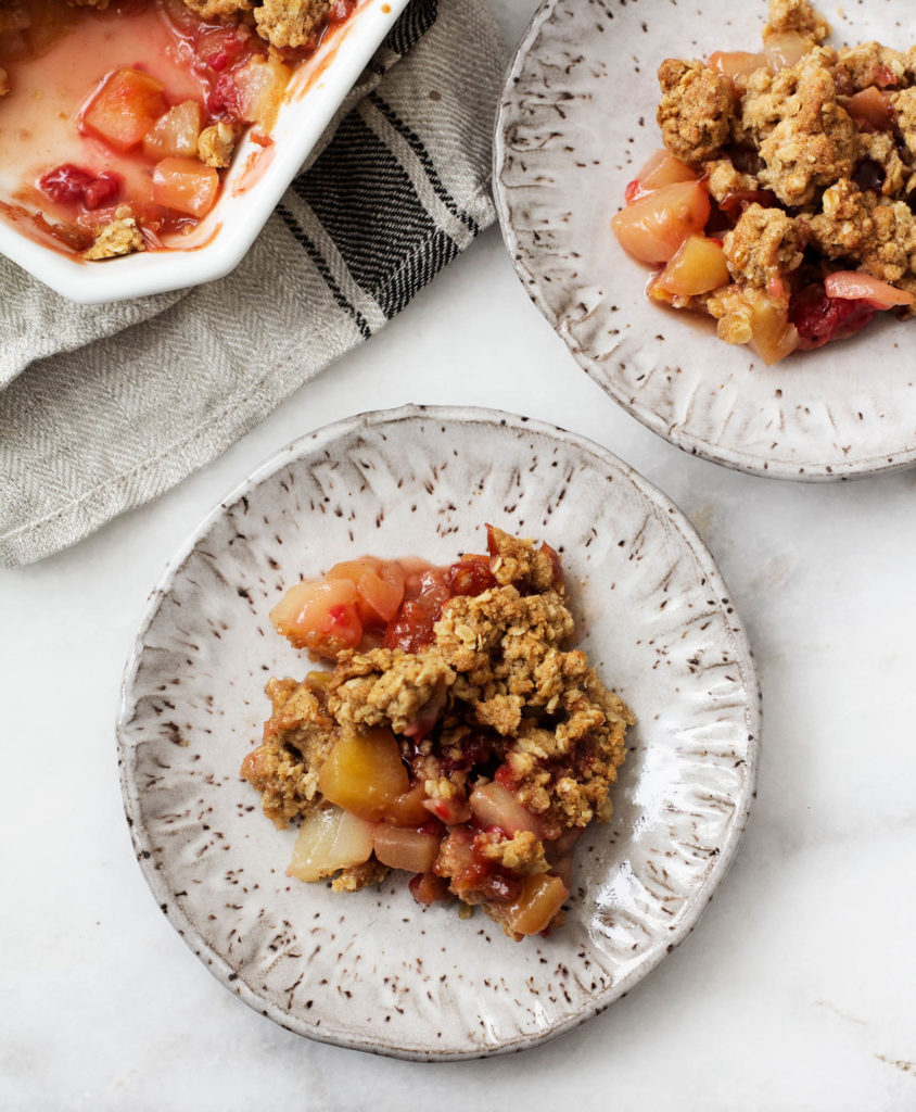 An overhead shot of a cozy vegan apple, pear & cranberry crisp, plated and ready to eat.