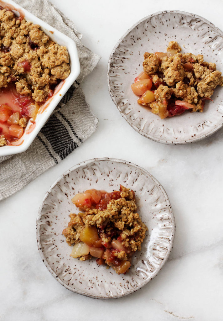 A baking dish and small plates of vegan crisp with apples and pears.