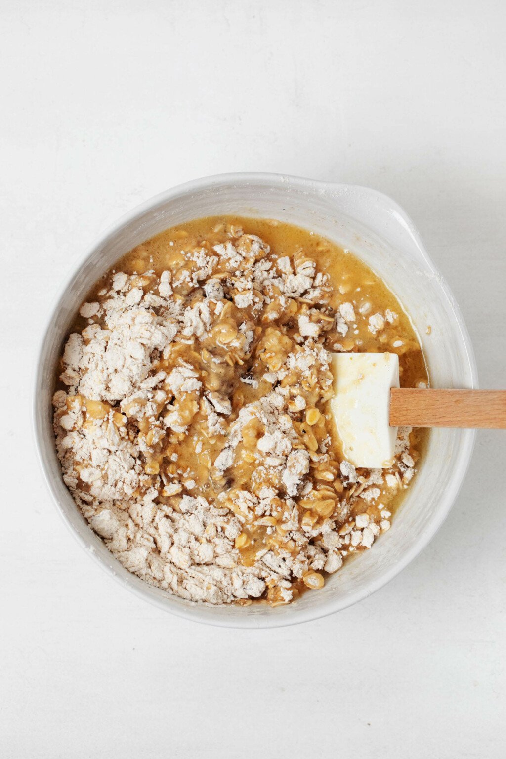 A large, white mixing bowl is being used to prepare a breakfast baked good.