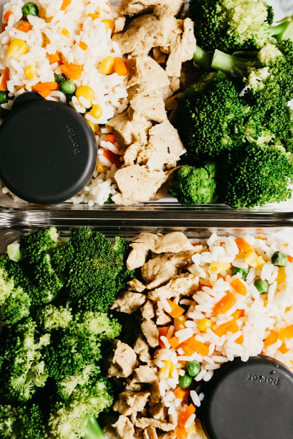 Two glass containers are full of a protein, broccoli, and rice. 