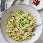 An overhead shot of a simple broccoli stem and brown rice stir fry, garnished with crushed red pepper flakes.