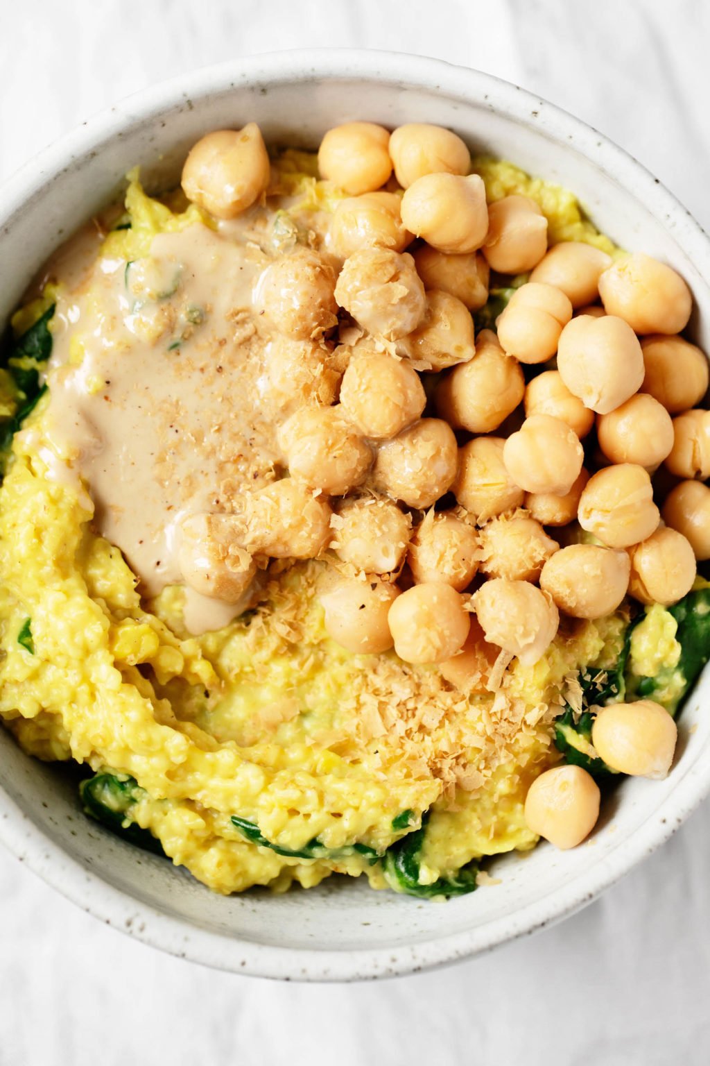 A zoomed in, overhead photograph of a vegan grain dish with legumes and spinach.